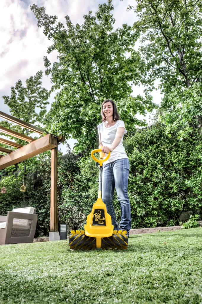 Mujer limpiando y peinando cesped artificial con Roll&Comb 141E vertical